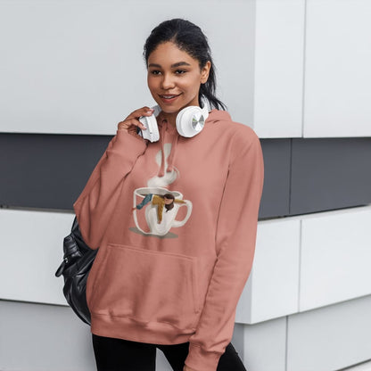 Person wearing a pink hoodie with a graphic design, holding headphones, in a modern interior setting.