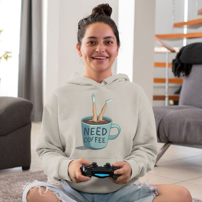 Person wearing a hoodie with a coffee-themed design, holding a gaming controller in a living room.