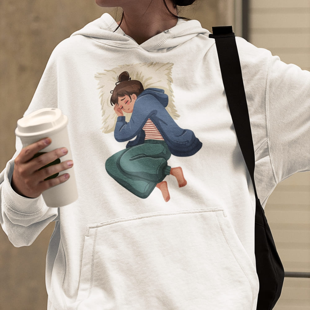 Person wearing a white hoodie with a graphic design of a couple on a pillow, holding a coffee cup.