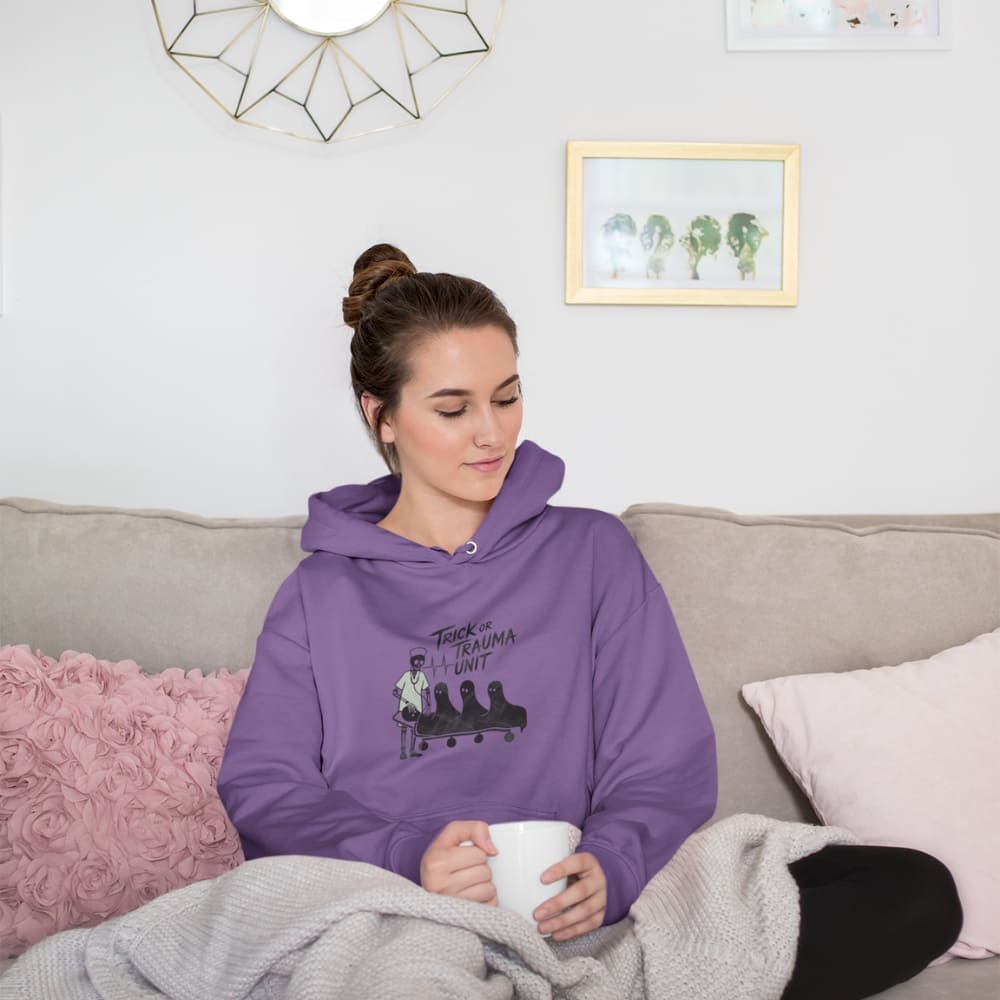 Woman wearing a purple hoodie with a graphic design, sitting on a couch holding a mug.