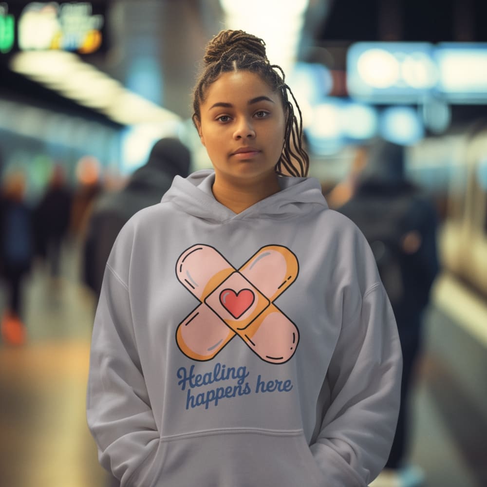 Person wearing a hoodie with a bandage and heart design in an urban setting