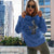 Woman wearing a blue hoodie with a graphic design in an urban setting