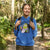 Person wearing a blue hoodie with a cartoon character in a forest
