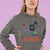 Person wearing a gray hoodie with a graphic design and text on a purple background