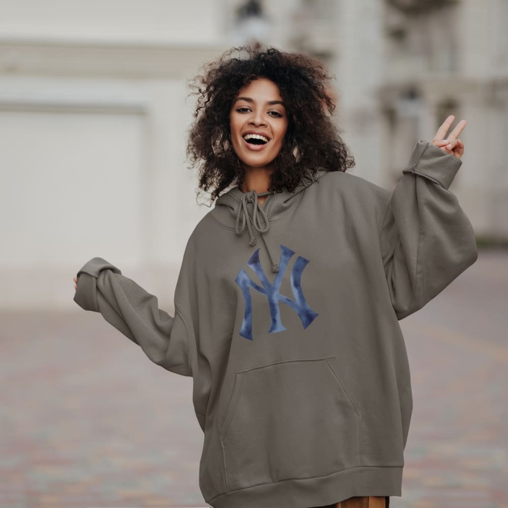 Woman wearing a gray hoodie with a blue logo, making a peace sign outdoors.