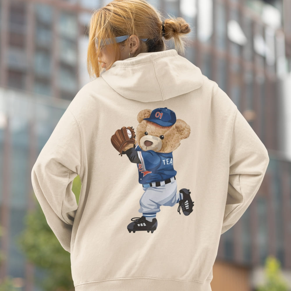 Person wearing a hoodie with a teddy bear graphic in a city setting