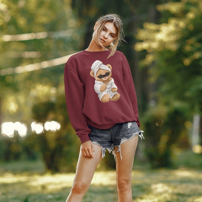Woman wearing a maroon sweatshirt with a teddy bear graphic in a park setting