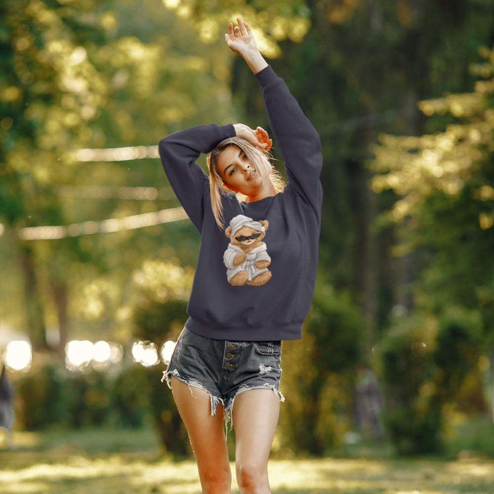 Woman in a navy sweatshirt with a teddy bear graphic in a park