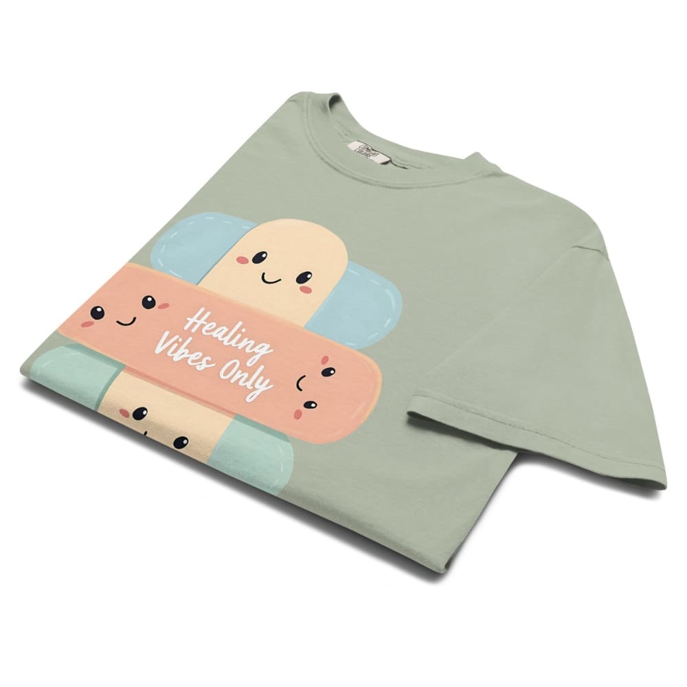 Green t-shirt with cartoon bandages and 'Healing Vibes Only' text on a white background
