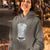 Person wearing a hoodie with a '100% Caffeine Drip Stat' design outdoors.