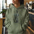 Person wearing a green hoodie with a graphic design in an indoor setting