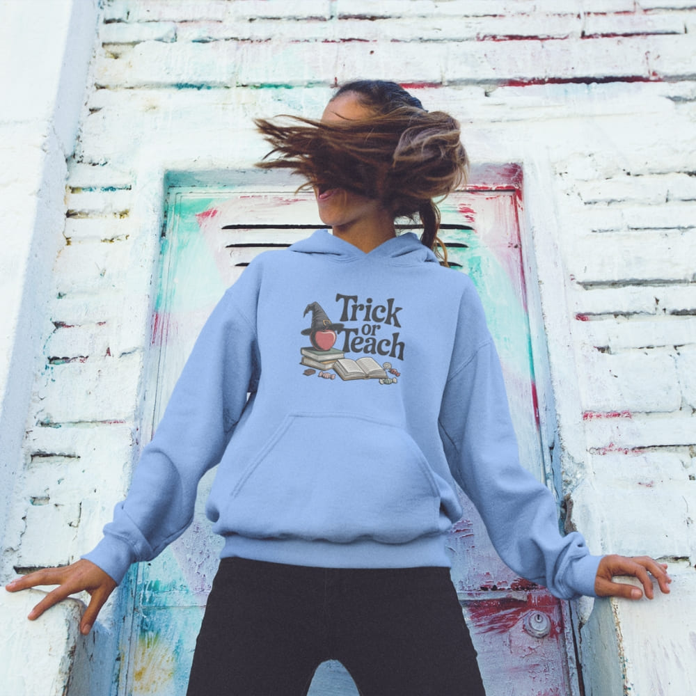 Person wearing a blue hoodie with 'Trick or Teach' design against a colorful wall.