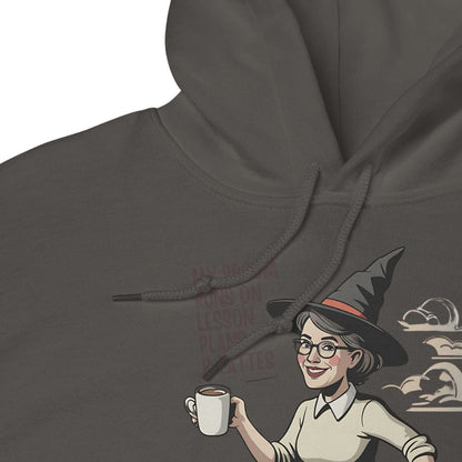 Hoodie with a design of a person wearing a witch hat and holding a coffee cup, set against a dark gray background.