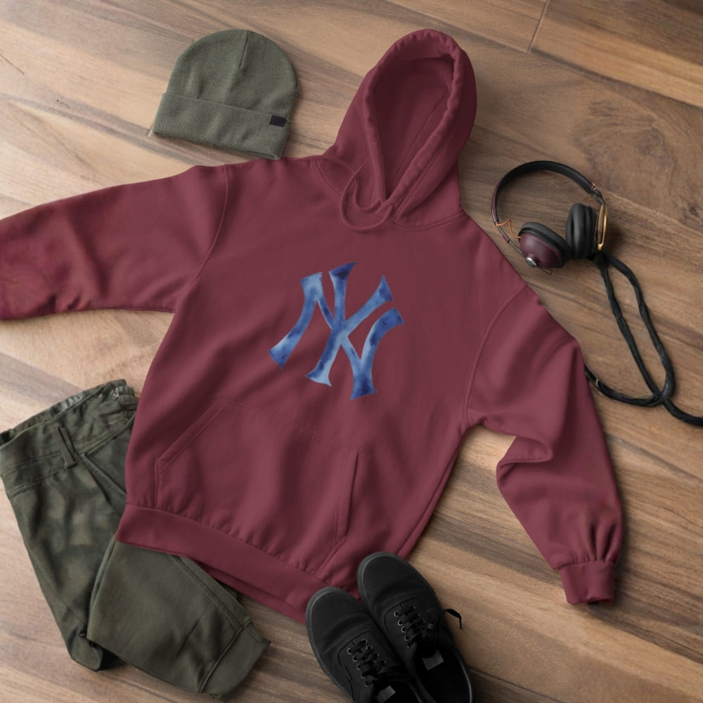 Maroon hoodie with blue logo, green beanie, black shoes, and headphones on a wooden floor.