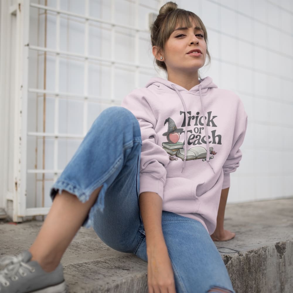 Person wearing a pink hoodie with 'Trick or Teach' text and sitting on steps.