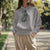 Person wearing a gray hoodie with a graphic design outdoors