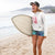 Person holding a surfboard on a beach with mountains in the background