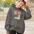 Person wearing a gray hoodie with a graphic design and text, standing outdoors.