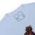 Light blue t-shirt with a label and a design of a bun on a white background