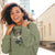 Woman wearing a green hoodie with a graphic design, standing outdoors.