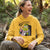 Person wearing a yellow hoodie with a cartoon character in a forest setting