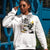 Person wearing a white hoodie with graphic design in front of a blue door.