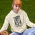 Person wearing a hoodie with a graphic design sitting on grass
