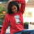 Person wearing a red hoodie with a graphic design, sitting outdoors.