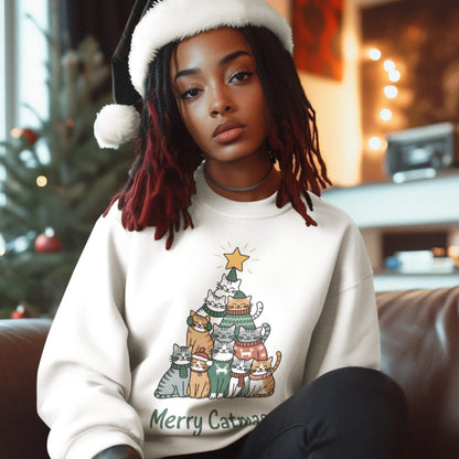 Person wearing a white sweatshirt with a cat-themed Christmas tree design, sitting in a cozy room with festive decorations.
