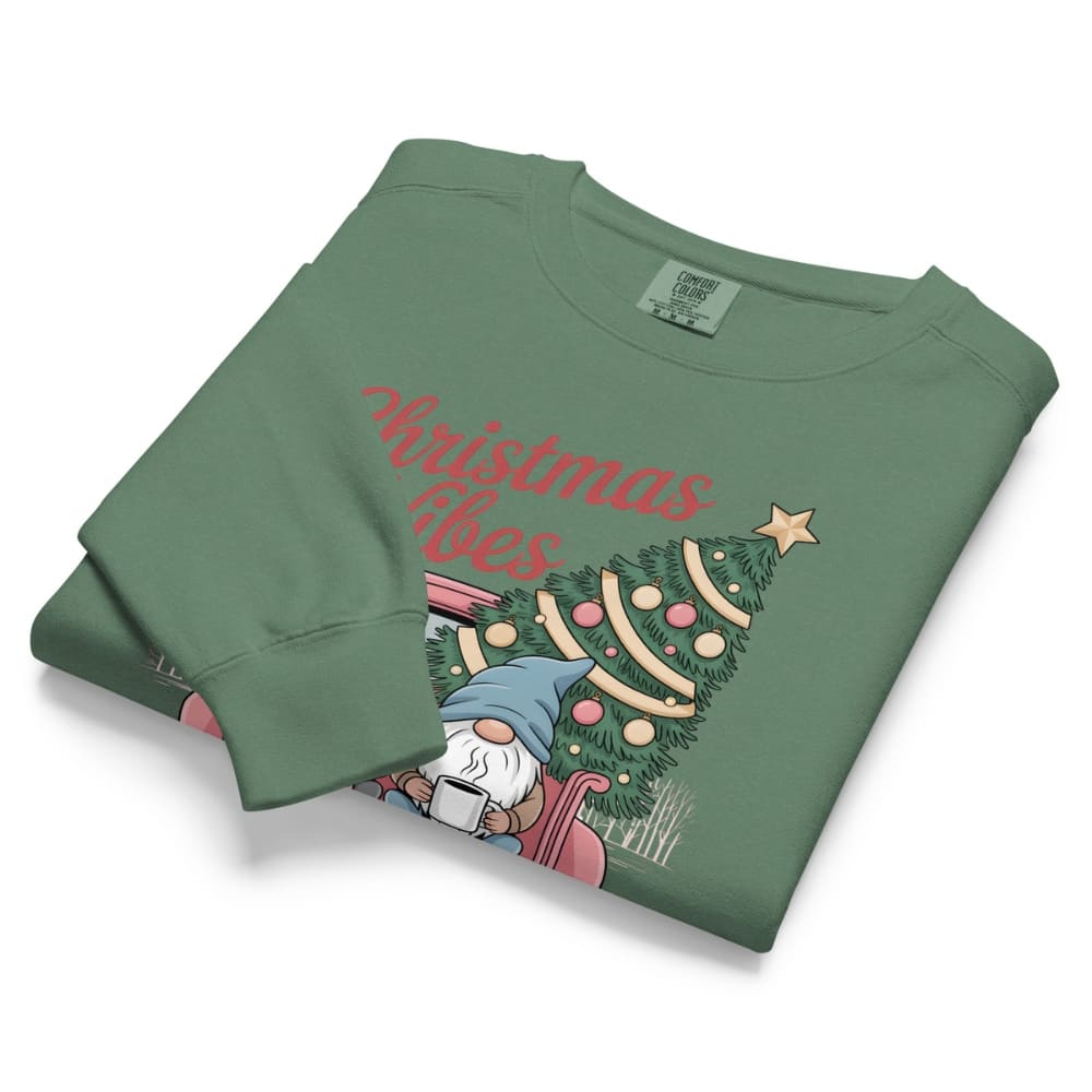 Folded green sweatshirt with Christmas design and text on a white background