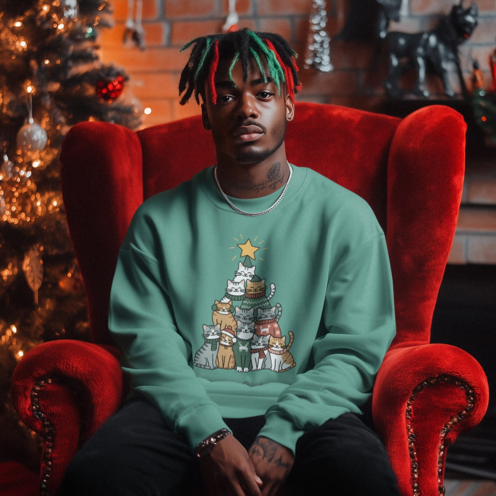 Person wearing a green sweater with a Christmas tree design, sitting on a red chair in front of a decorated Christmas tree.