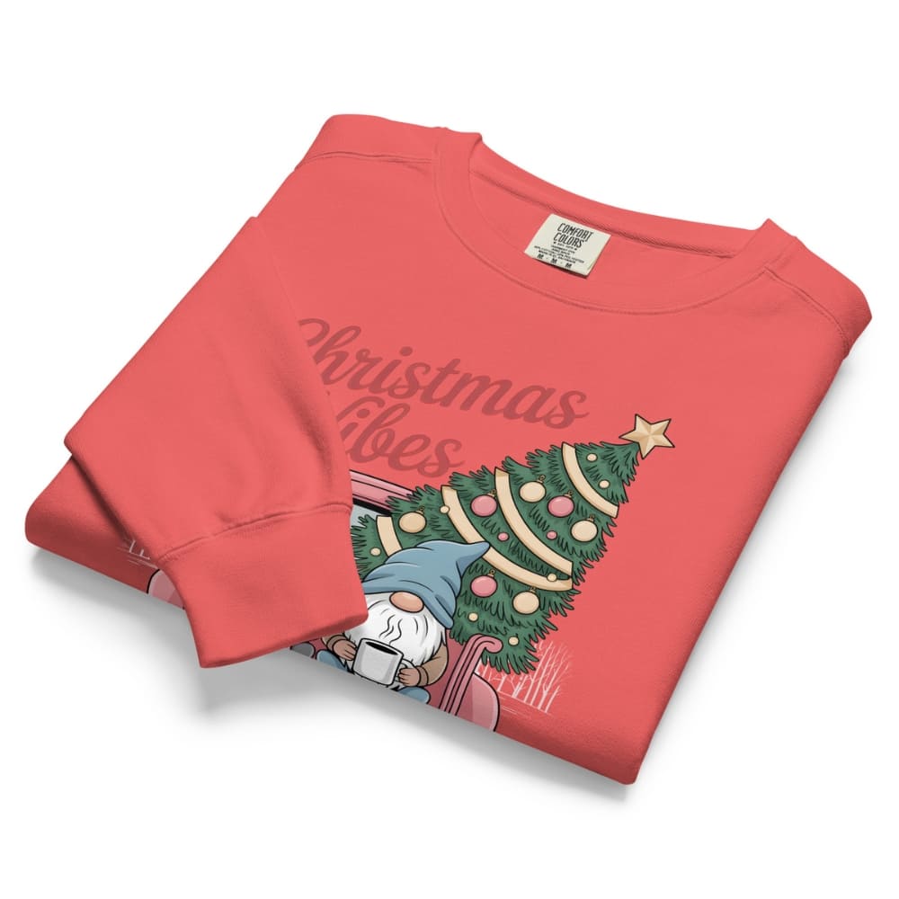 Folded red sweatshirt with Christmas tree and gnome design on a white background