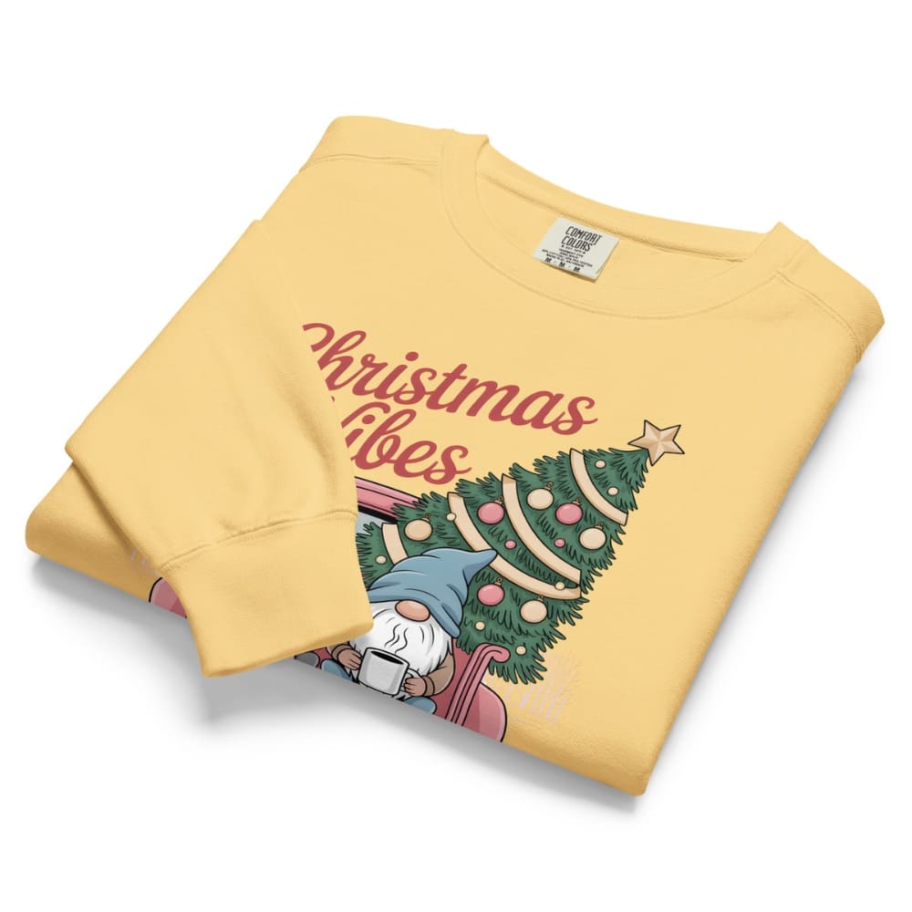 Folded yellow sweatshirt with Christmas design and text on a white background