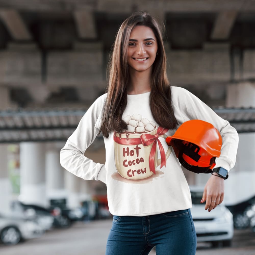 Woman wearing a 'Hot Cocoa Crew' shirt with a helmet, standing in an outdoor setting.