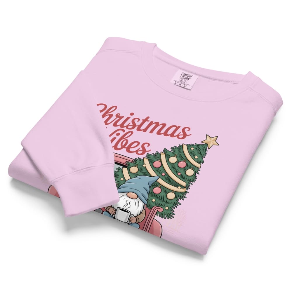 Folded pink sweatshirt with Christmas design and text on a white background