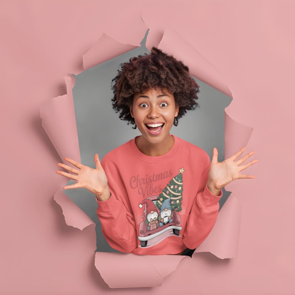 Person wearing a pink 'Christmas Vibes' sweatshirt with a tree design, standing through a pink paper cutout.