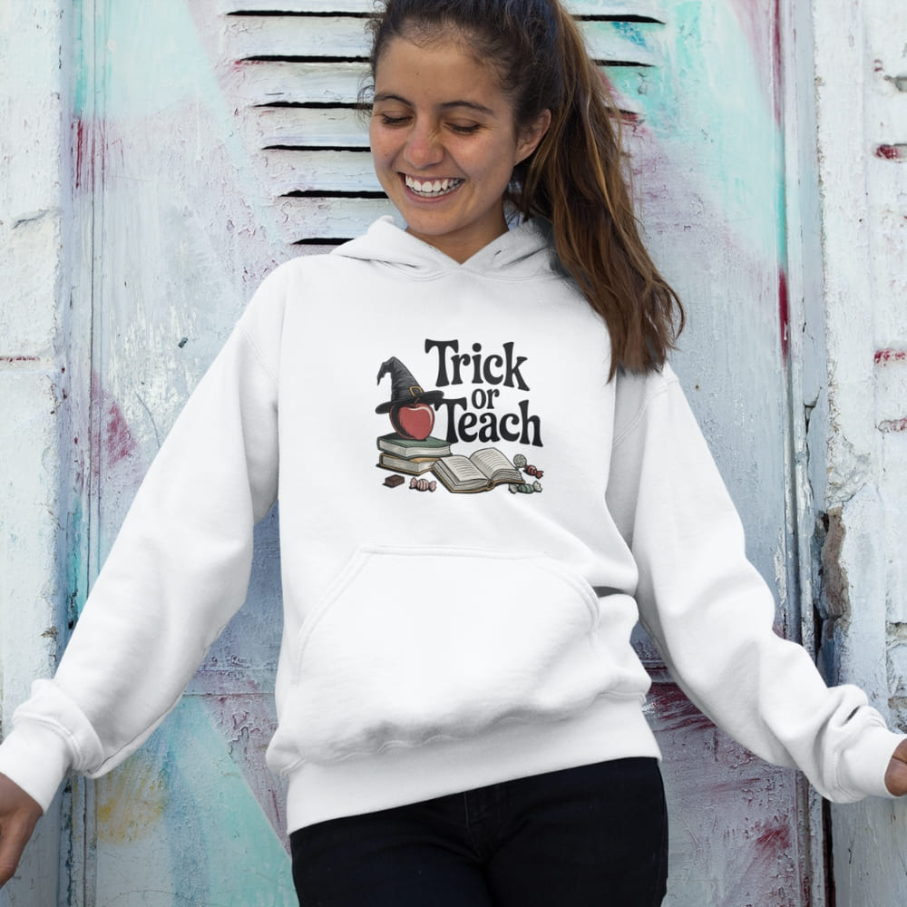 Person wearing a white hoodie with 'Trick or Teach' design against a textured wall.