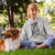 Woman sitting on grass with a dog, wearing a hoodie with a graphic design.