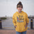 Person wearing a yellow 'Trick or Teach' hoodie with a witch hat graphic.