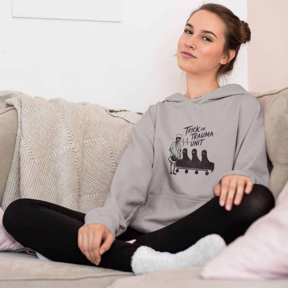 Woman wearing a gray hoodie with a graphic design sitting on a couch.