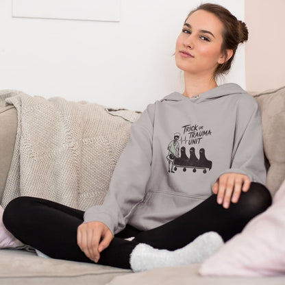 Woman wearing a gray hoodie with a graphic design sitting on a couch.