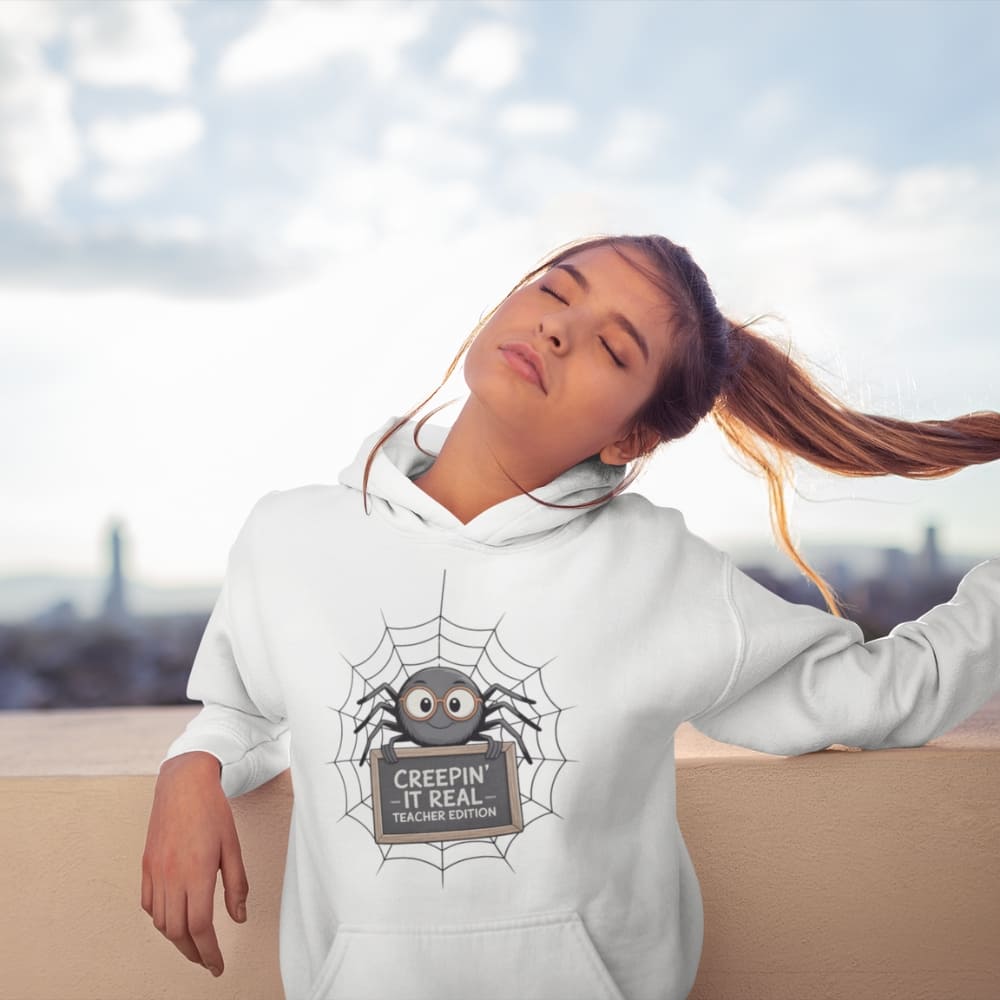 Person wearing a white hoodie with a spider graphic and text, sitting outdoors.