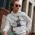 Woman wearing a white hoodie with a graphic design and text, sitting outdoors.