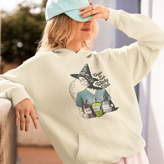 Person wearing a beige hoodie with a graphic design, sitting outdoors.