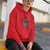 Person wearing a red hoodie with a spider graphic and text, sitting outdoors.