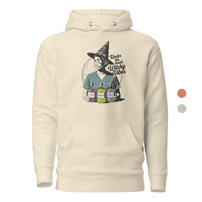 Beige hoodie with a graphic of a person in a witch hat holding potion bottles and text 'Under the Influence Witchy Vibes'.