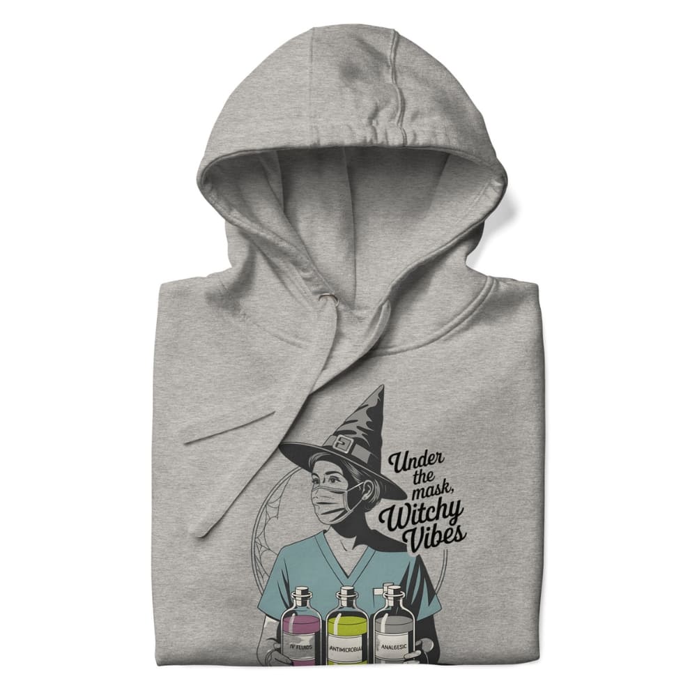 Gray hoodie with a graphic design of a person wearing a witch hat and text 'Under the mask, Witchy Vibes' on a white background.