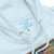 Close-up of a white hoodie with a brand label on the chest pocket.