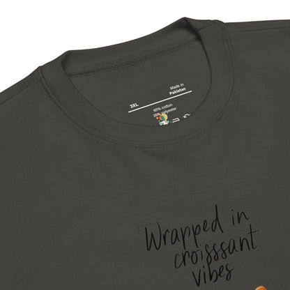 Dark gray t-shirt with 'Wrapped in croissant vibes' text and brand label on a white background
