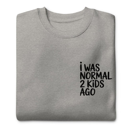 Folded gray sweatshirt with black text 'I WAS NORMAL 2 KIDS AGO' on a white background
